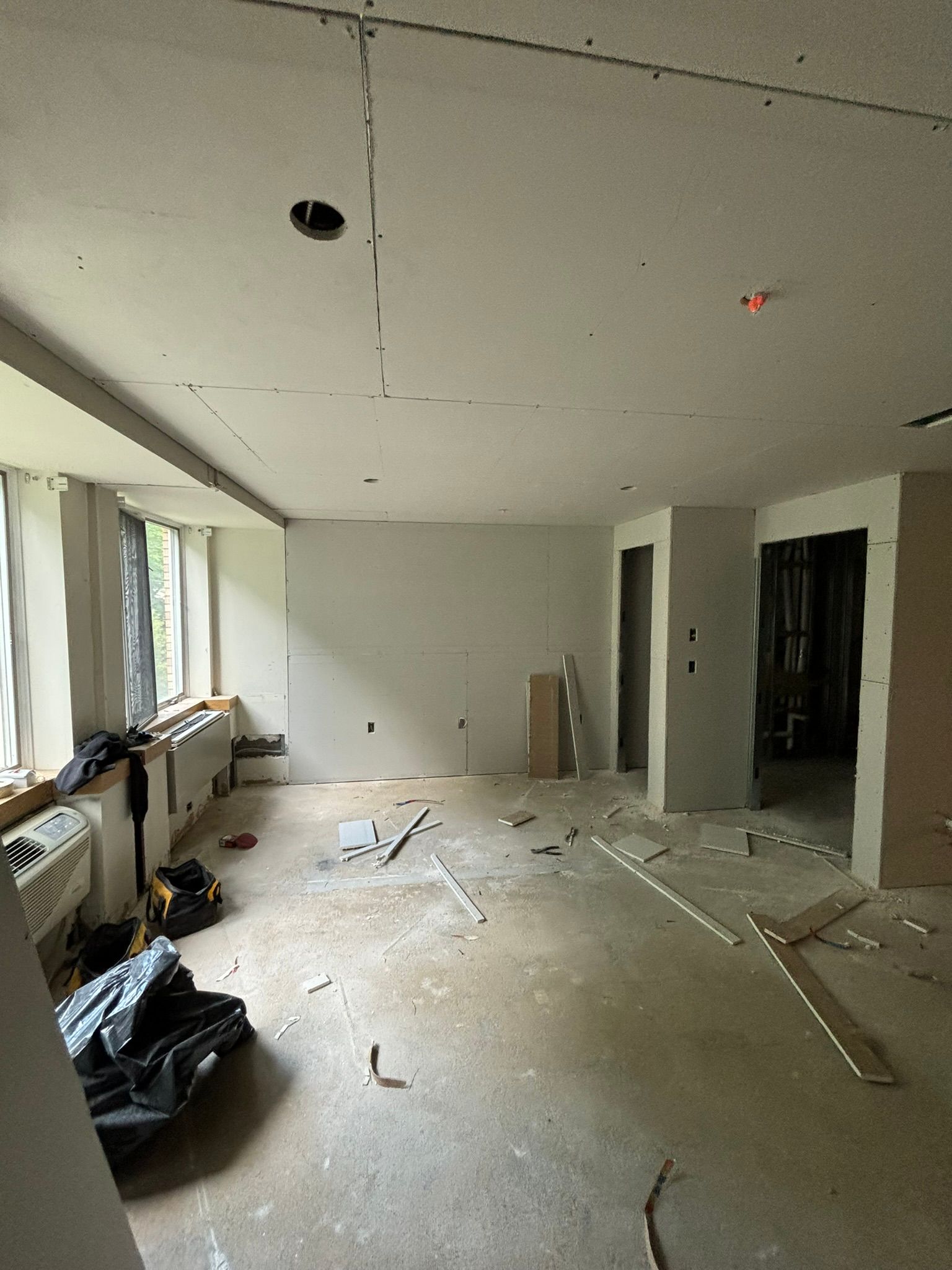 Interior renovation: Unfinished room with drywall, tools, and construction debris.