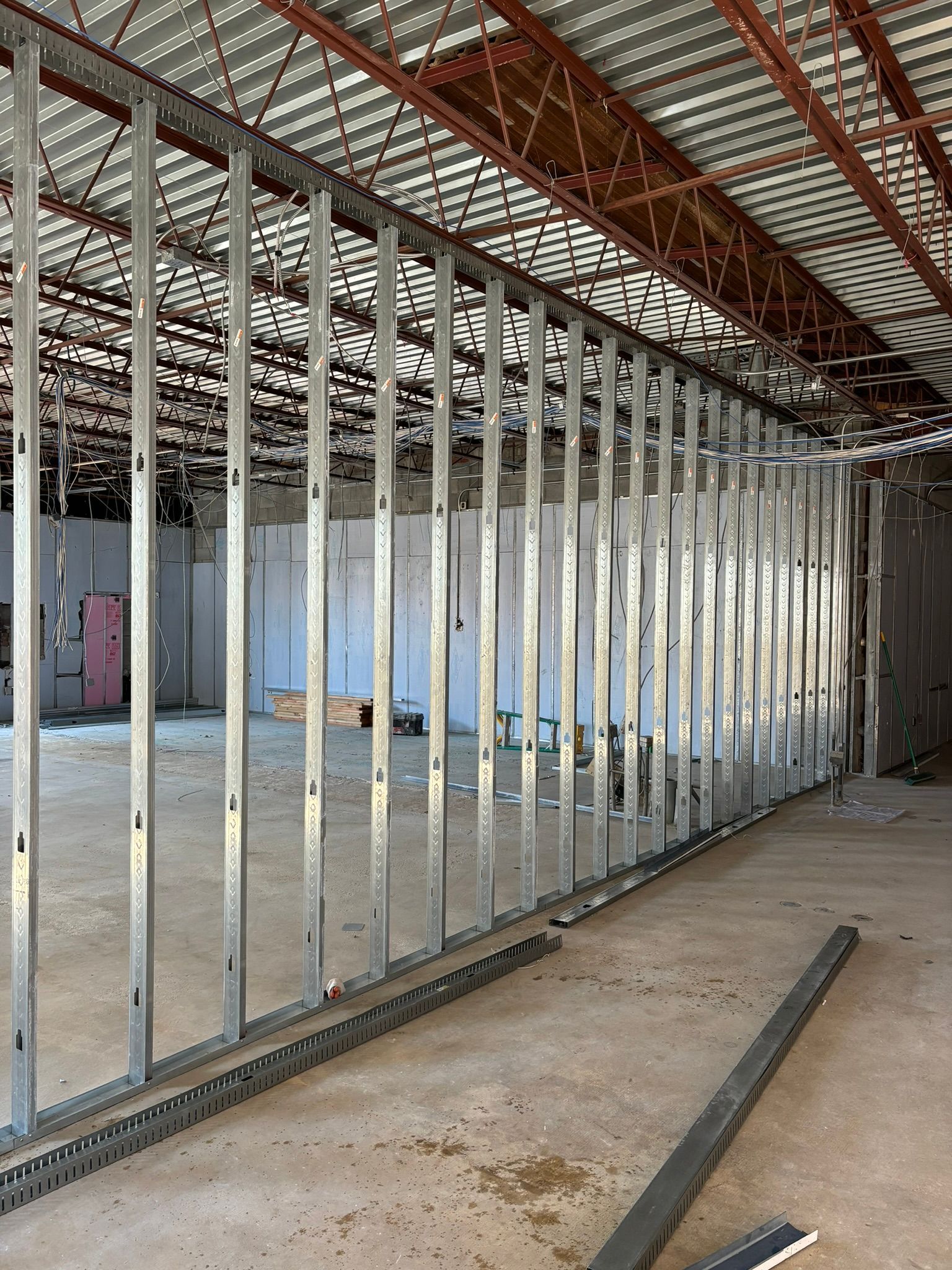 Metal studs form a wall within a building under construction, revealing the open interior.