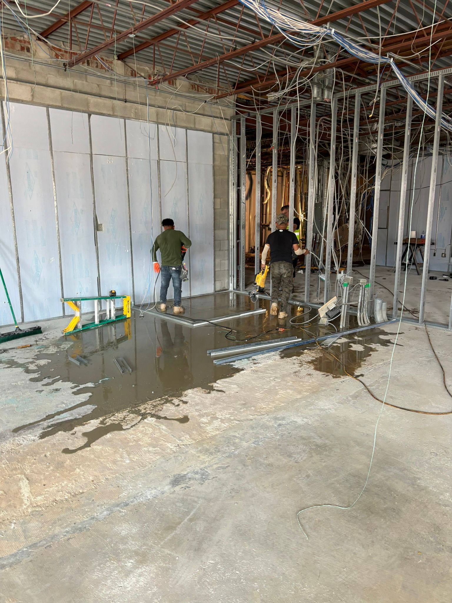 Construction workers installing walls in a building interior, tools and materials present.