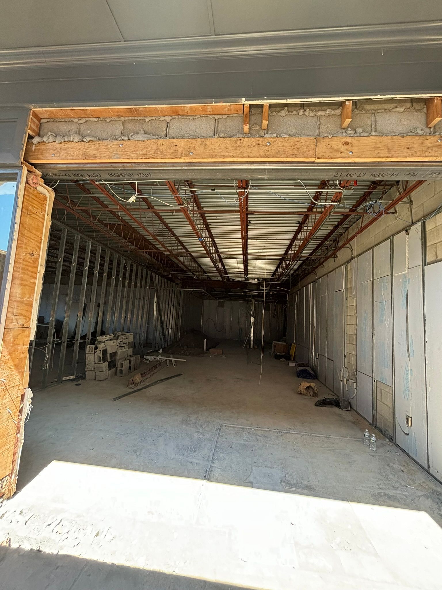 Interior of a building under construction, showing a long, empty space with exposed framework.