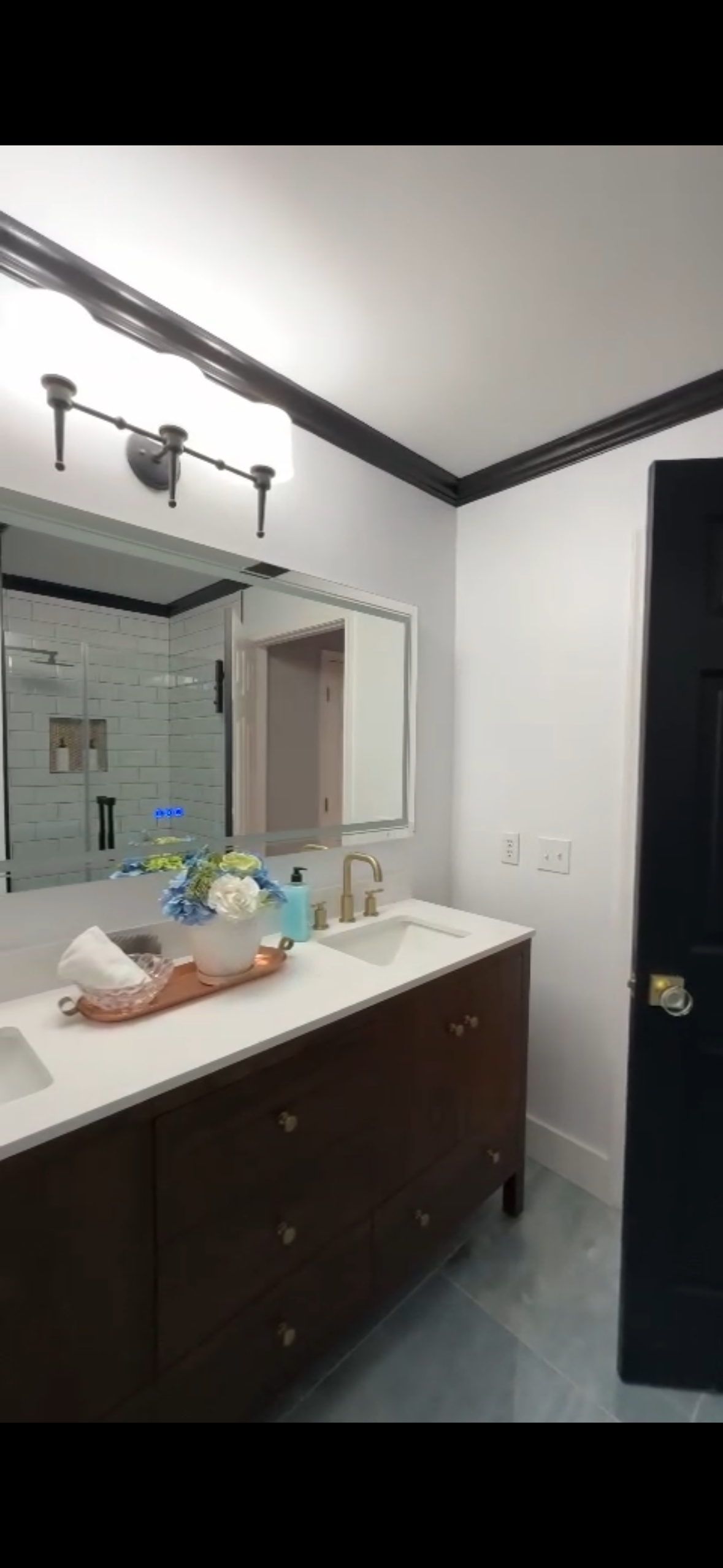 Bathroom with a dark brown vanity, black trim, and white walls.