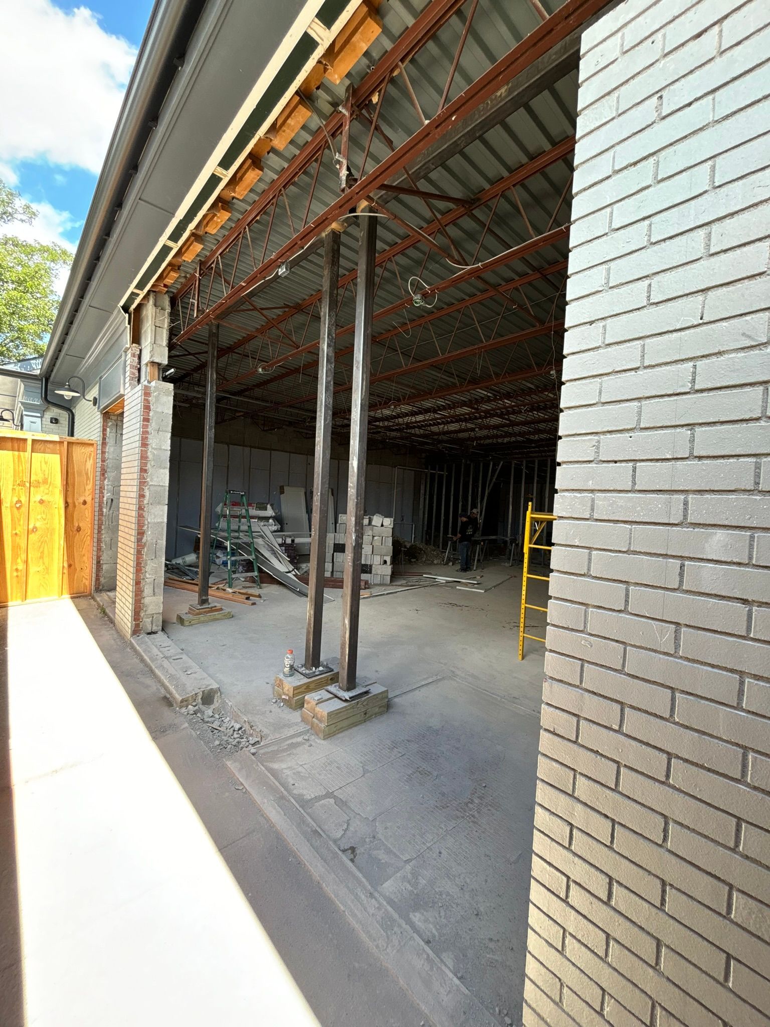 Construction site: Brick building with open interior, temporary supports, and exposed roofing materials.