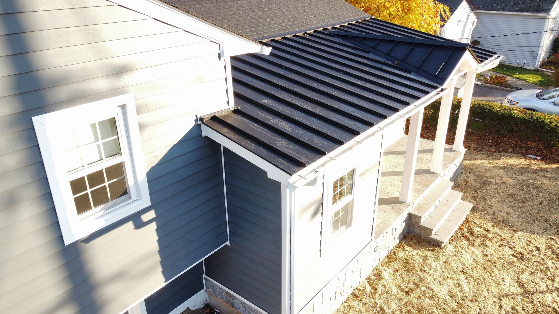 Dark blue house with dark metal roof, white trim, and small porch.
