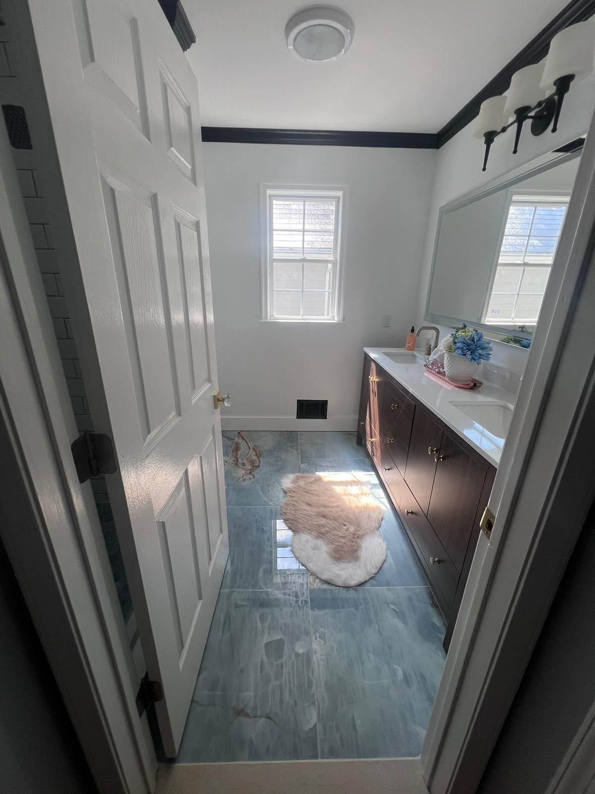 Bathroom interior with blue tile floor, white walls, dark trim, and a vanity.