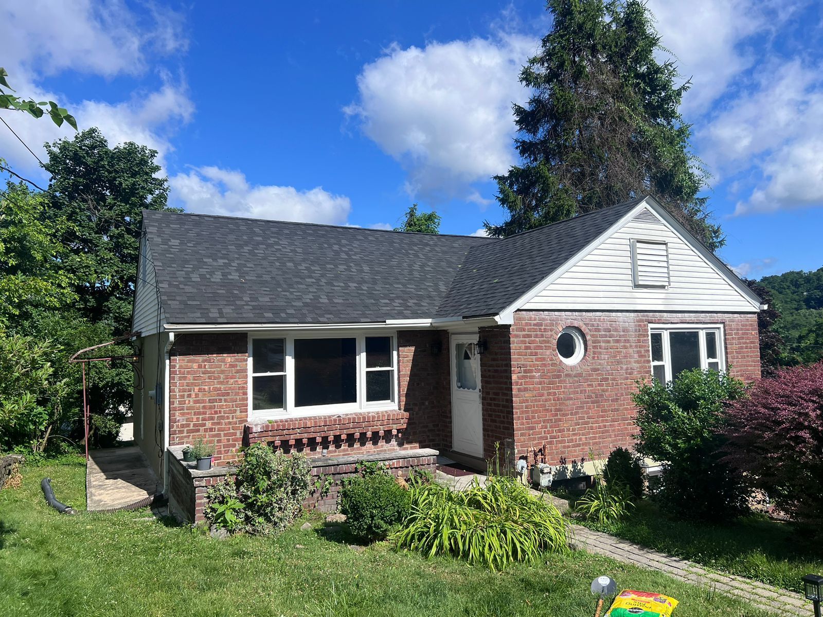Brick house with dark roof, white trim, and a small front porch on a sunny day.