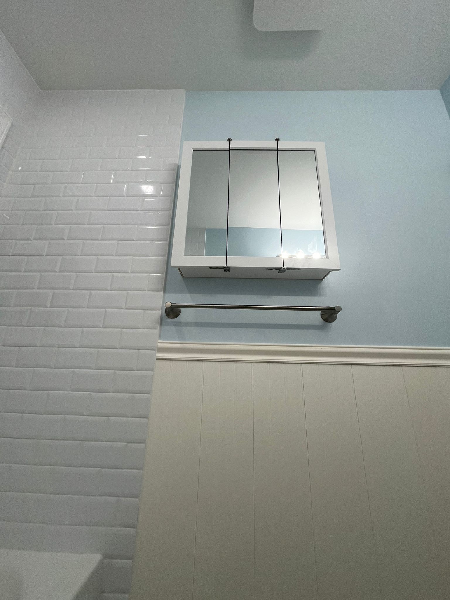 White bathroom with a medicine cabinet and towel rack.