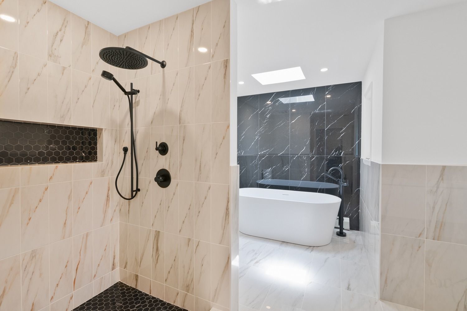 Modern bathroom with walk-in shower and black fixtures; separate soaking tub area with marble and black tile.