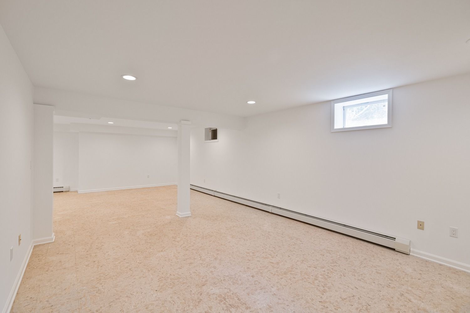 Empty, carpeted room with white walls, recessed lighting, and a small window.