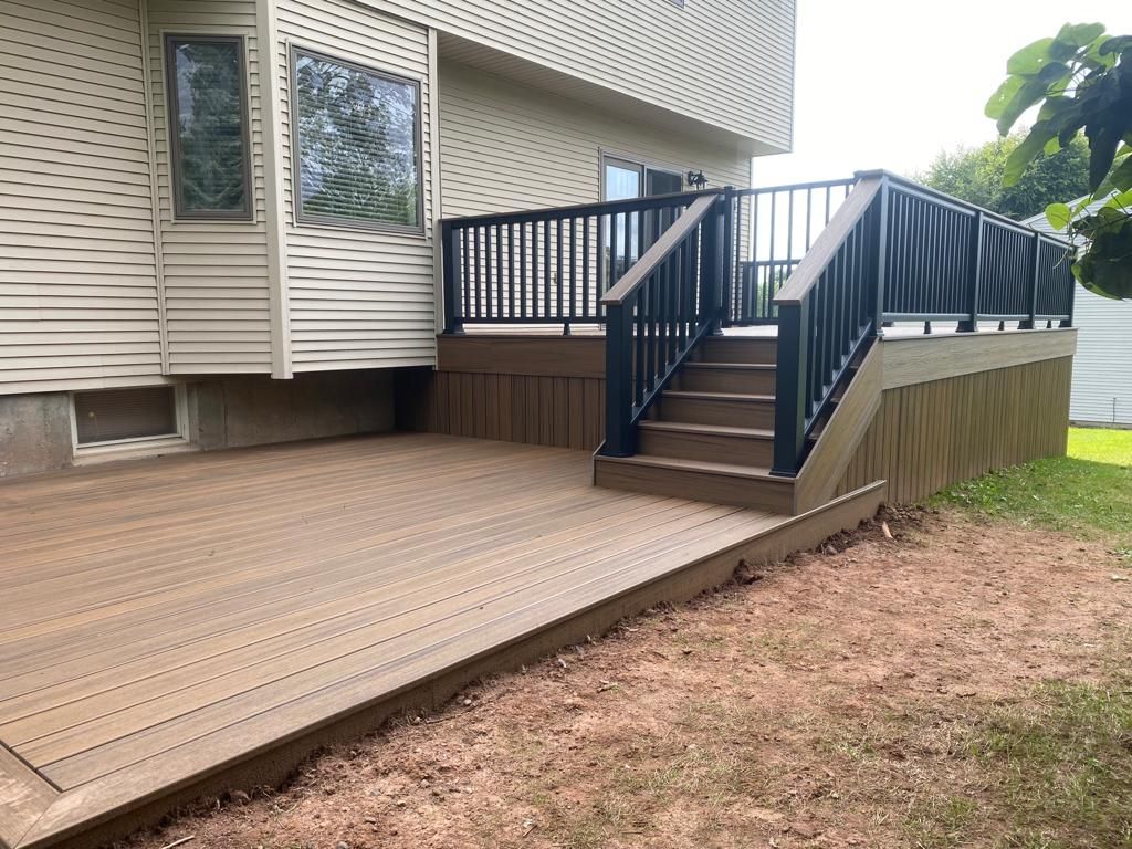 Composite deck with stairs and black railing against a light-colored house.