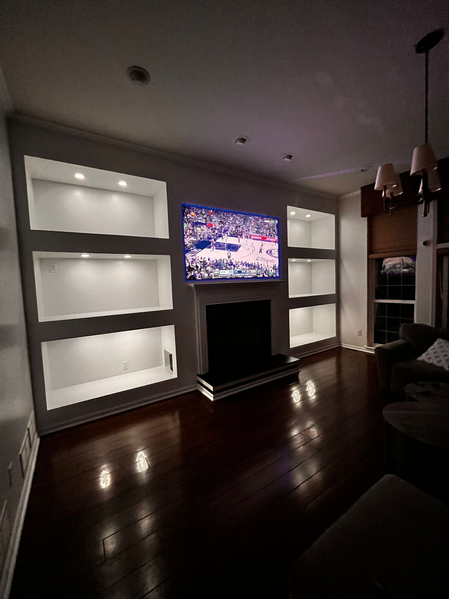 Living room with built-in shelves and a fireplace centered under a mounted TV.