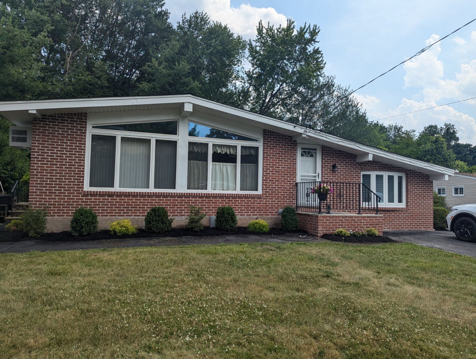 Brick ranch home with large windows, front porch, and manicured lawn.