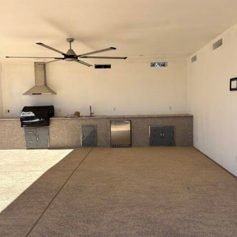 Covered patio with outdoor kitchen, ceiling fan, and beige carpeted floor in sunlight