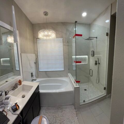 Modern bathroom with corner tub, glass shower, white vanity, and mirrored walls