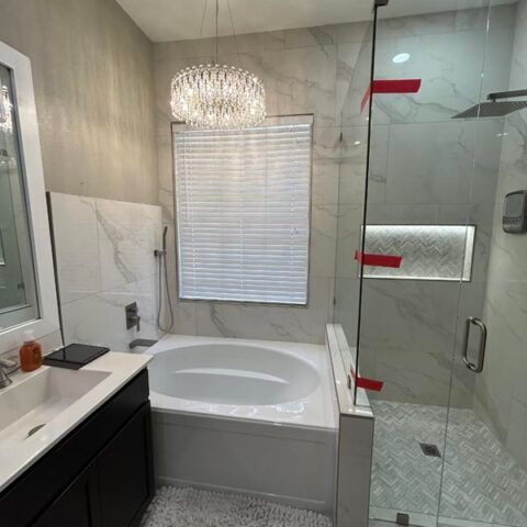 Modern bathroom with a freestanding tub, glass shower, dark vanity, and window blinds
