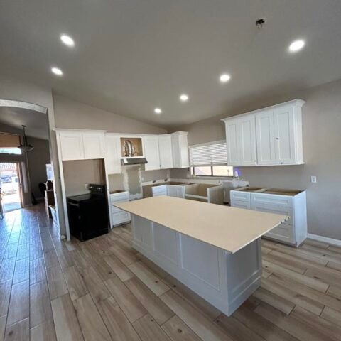 Bright modern kitchen with white cabinets, large island, stainless appliances, and wood-look tile floor