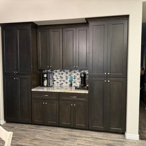 Dark wood kitchen cabinets with a built-in coffee station and tiled backsplash in a modern home.