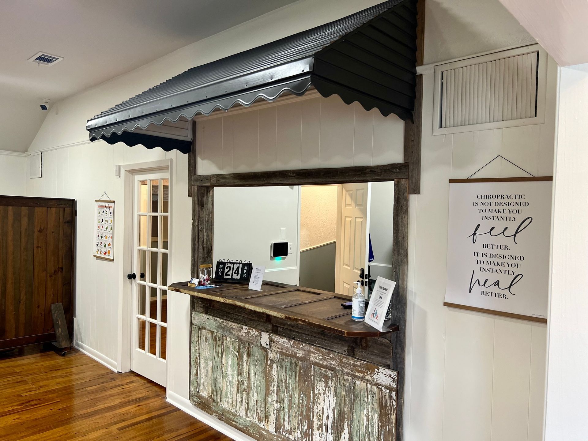 Rustic indoor reception window with counter, white walls, wood floor, and hanging sign art