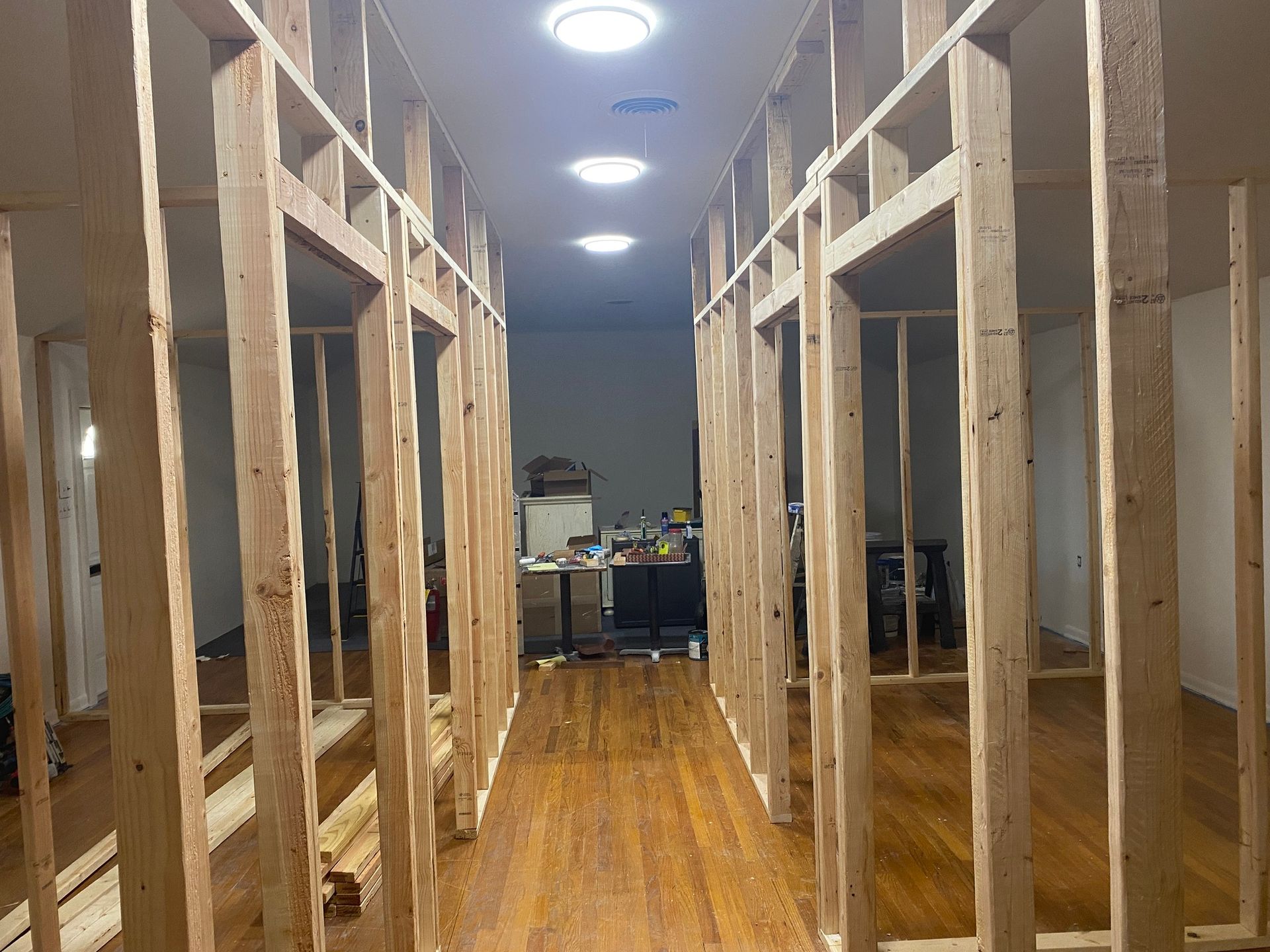 Empty hallway with unfinished wooden bunk bed frames on both sides and ceiling lights overhead