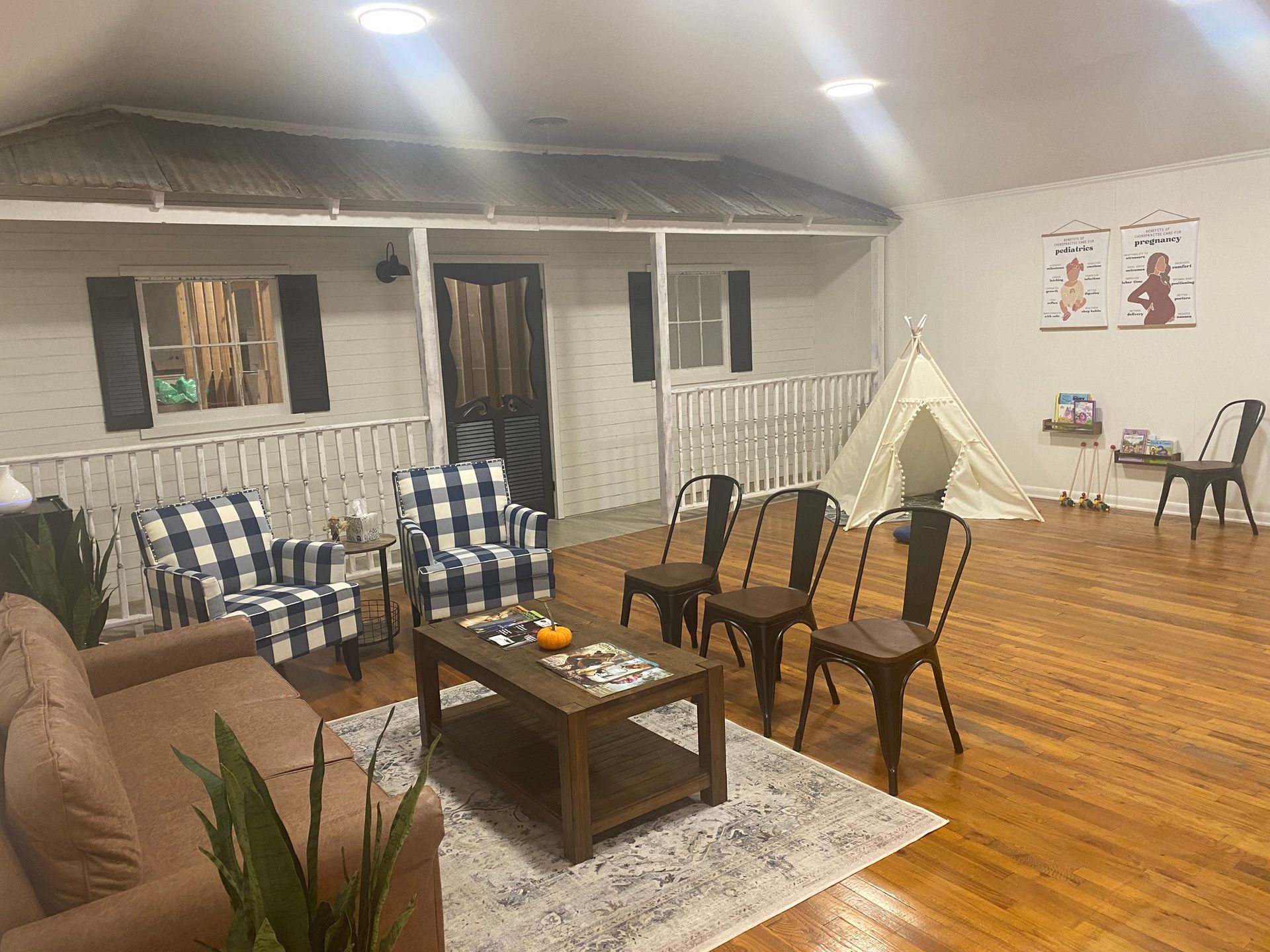 Cozy indoor lounge with plaid chairs, coffee table, rug, wood floor, and posters on the wall