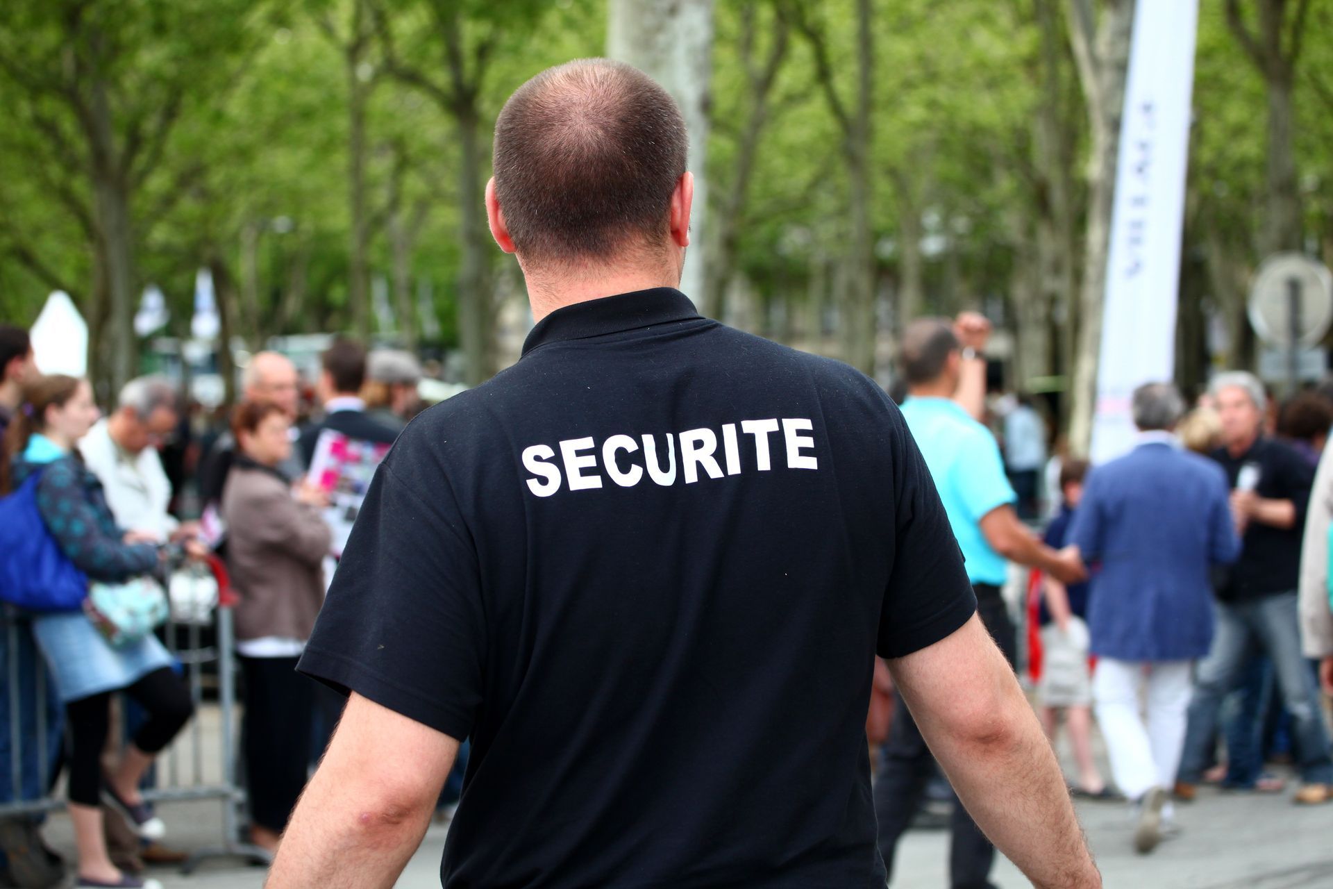 Un agent de sécurité se tient devant une foule de personnes.