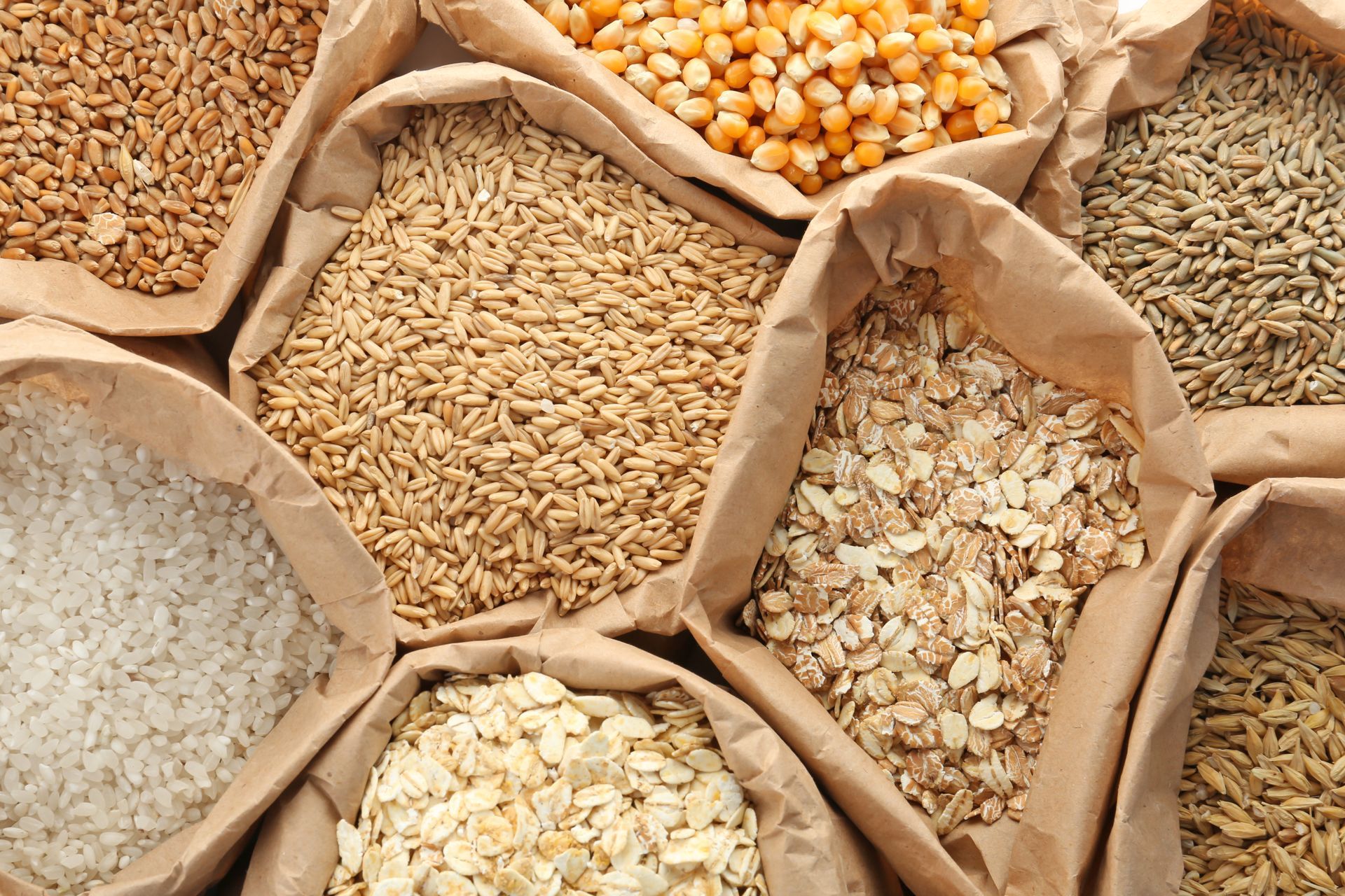 Assorted grains and legumes in burlap sacks, viewed from above