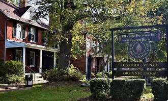 Historic house and sign at the Frederica Township Historic Village in green, tree-lined surroundings Historic house and sign at the Frederica Township Historic Village in green, tree-lined surroundings