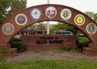 Brick archway entrance sign reading “Welcome to Glen Burnie” with civic emblems above it