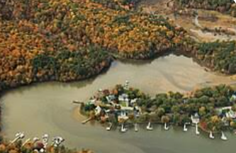 Aerial view of a small lakeside village surrounded by autumn-colored forest and water