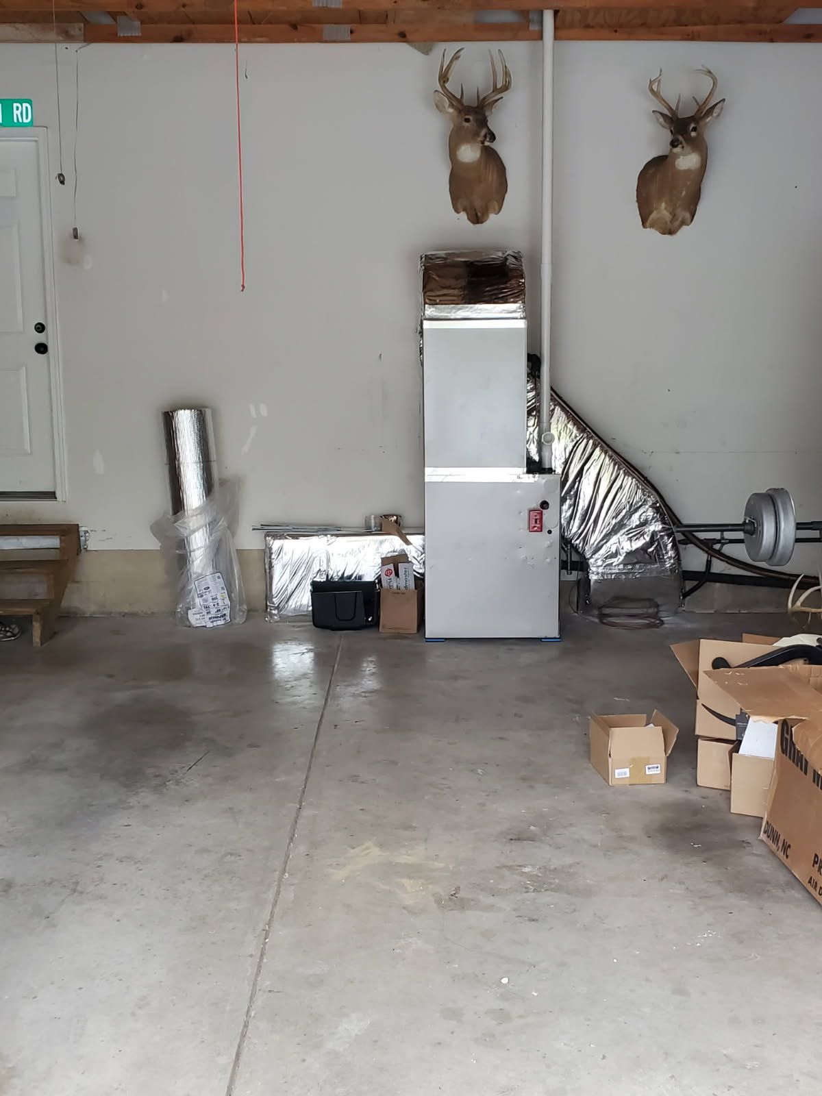 Garage with concrete floor, mounted deer heads, a silver cabinet, and scattered boxes and materials