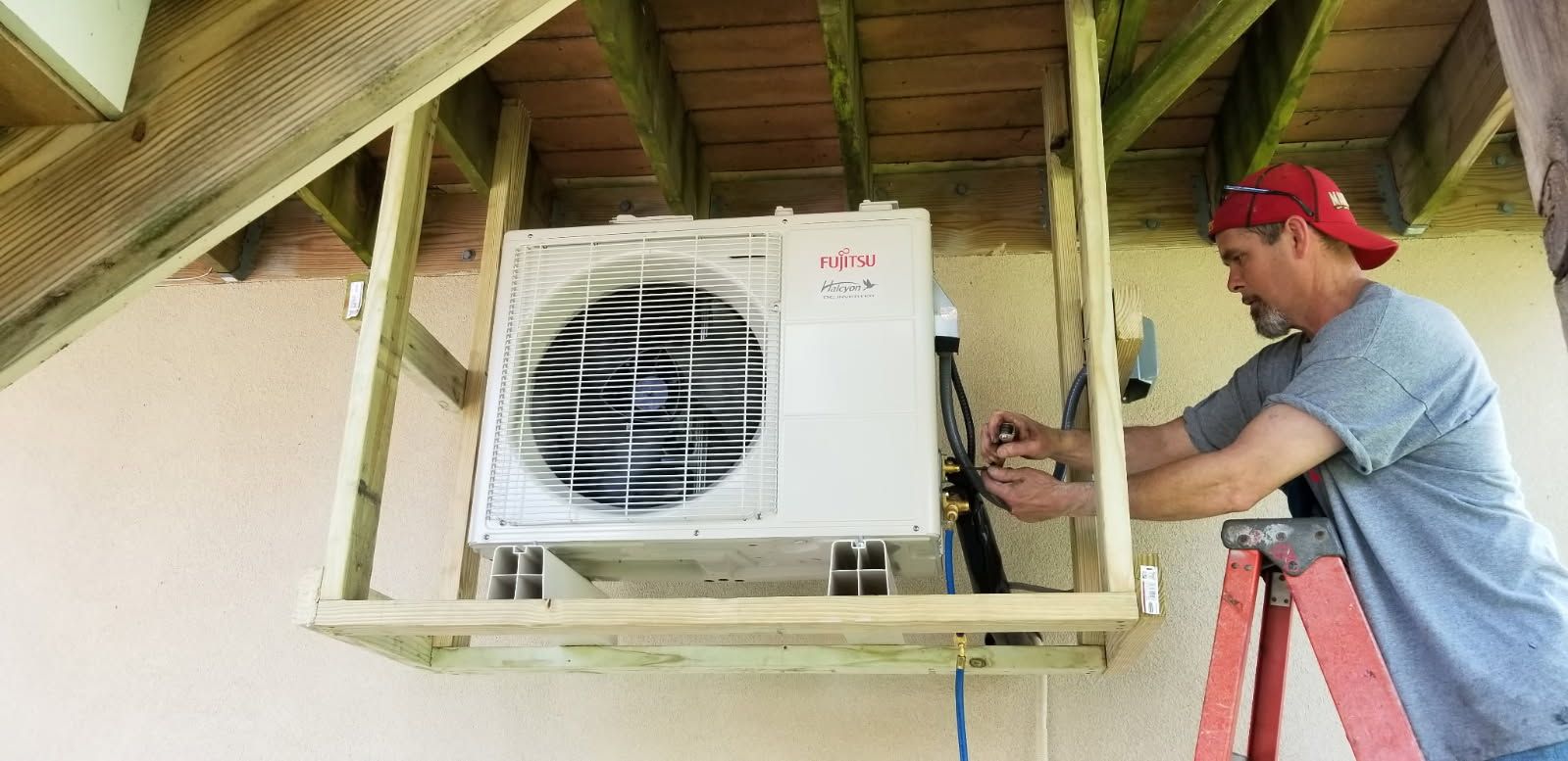 Technician repairing an outdoor air-conditioning unit under a porch roof