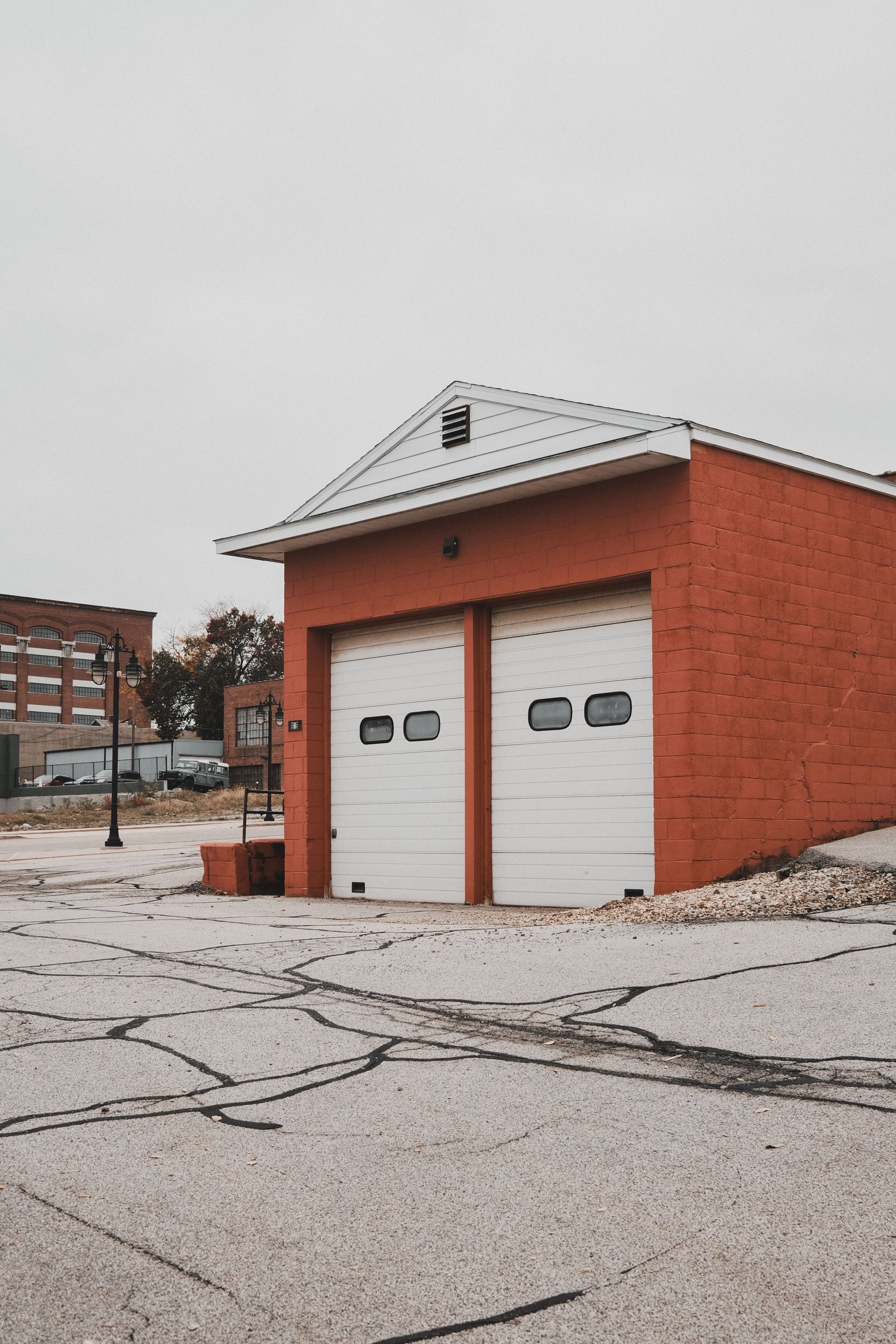Small red brick garage with two white doors in a snowy lot