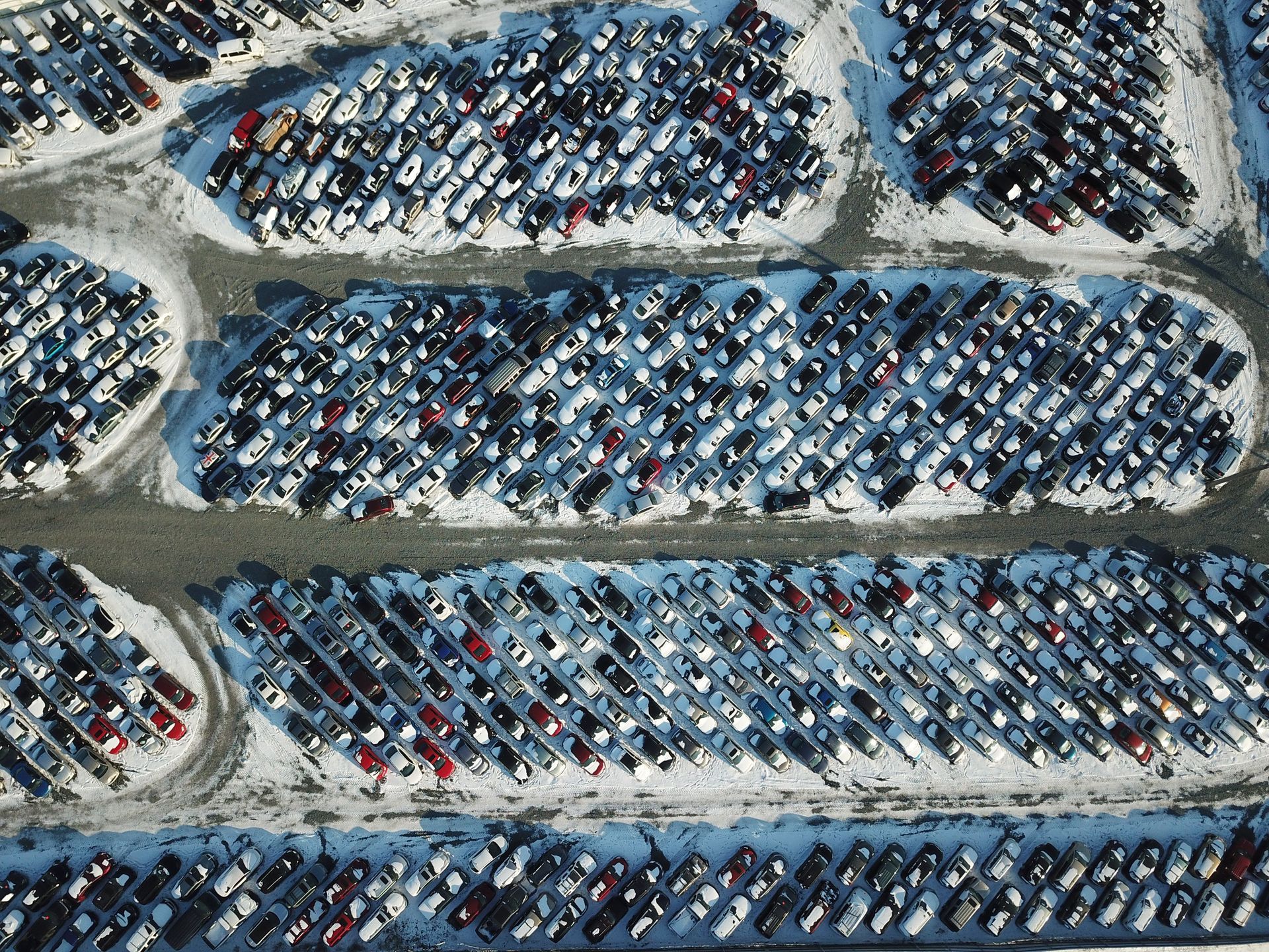 Aerial view of rows of parked cars in a crowded lot with dirt lanes between them