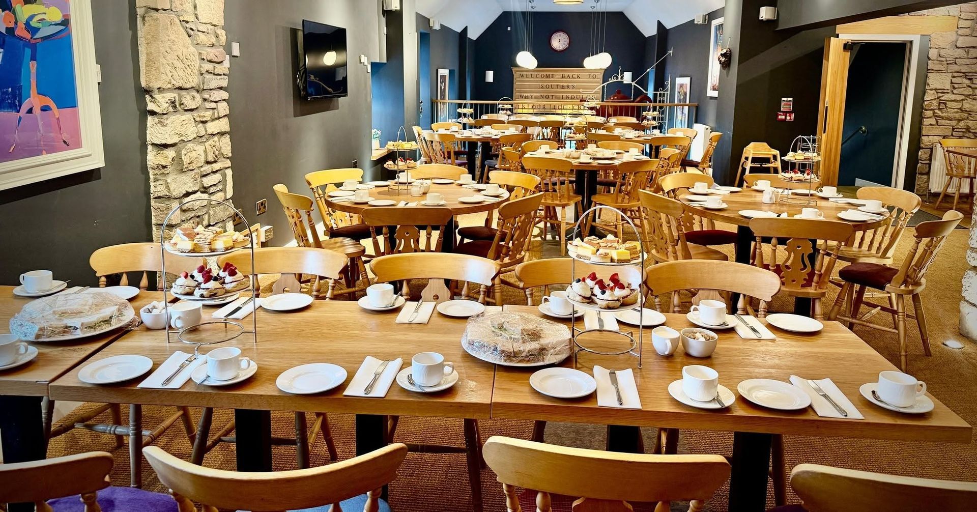 Set dining room with many wooden tables laid with white dishes and napkins, ready for guests