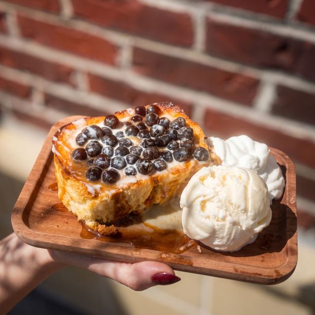 Handheld tray with bubble tea dessert slice and two scoops of vanilla ice cream outdoors