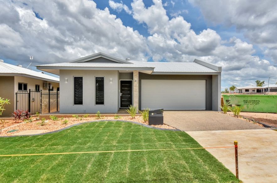 A White House with A Garage Door and A Lush Green Lawn in Front of It — Darwin Roller Door Services In Tivendale NT