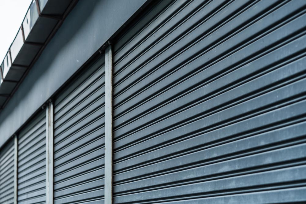 Closeup On Blue Roller Shutters Of A Commercial Building — Darwin Roller Door Services In Tivendale, NT