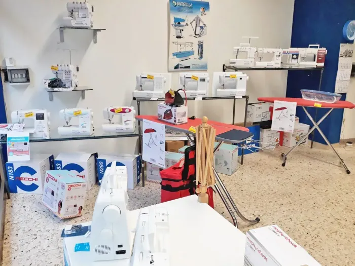 Macchine da cucire e materiali per il fai da te disposti su tavoli in un luminoso laboratorio.