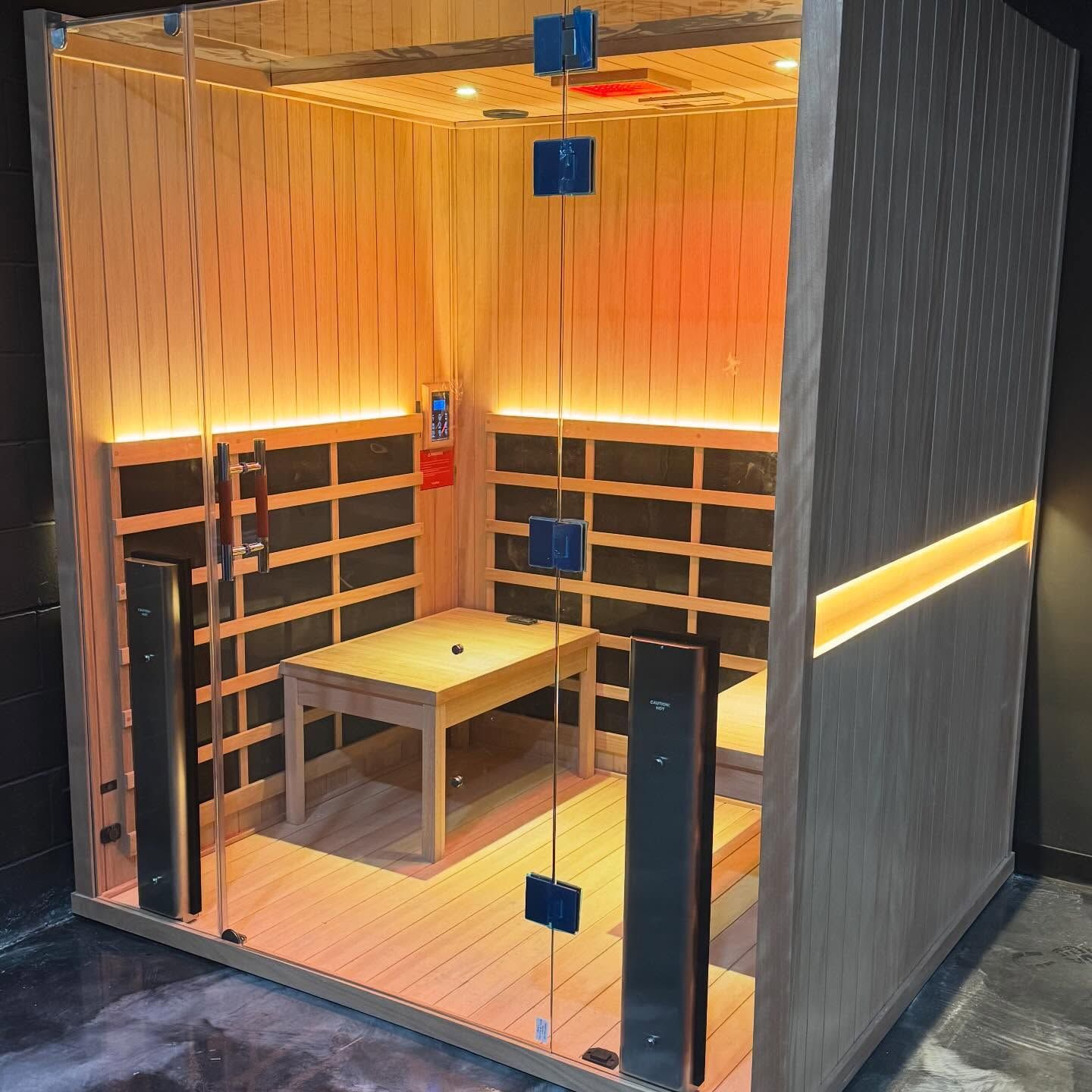 Empty modern room with wood slat walls, built-in shelves, a table, and warm yellow lighting.