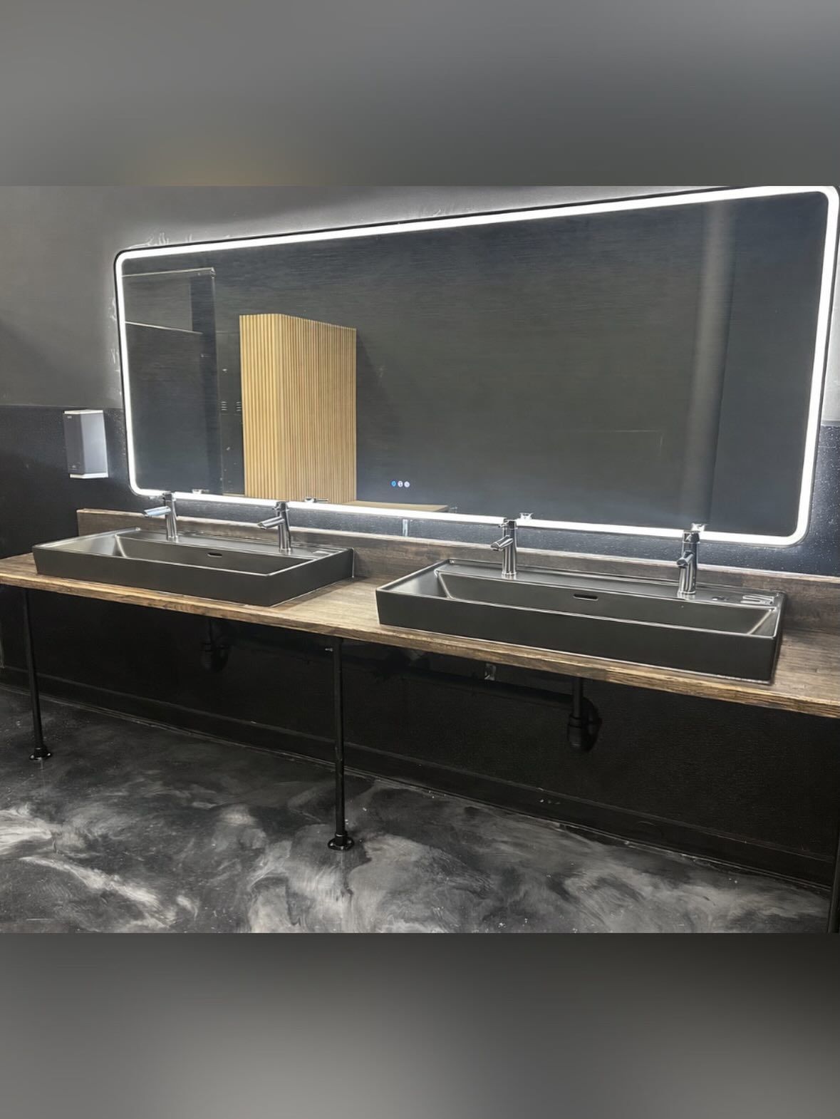 Modern black workstation with a large framed mirror, shelf, and two makeup-style trays on a marble floor