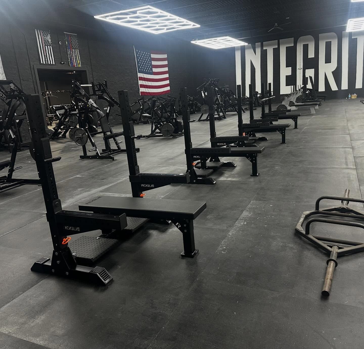 Empty gym with black equipment, American flag, and large “INTERIOR” wall lettering.