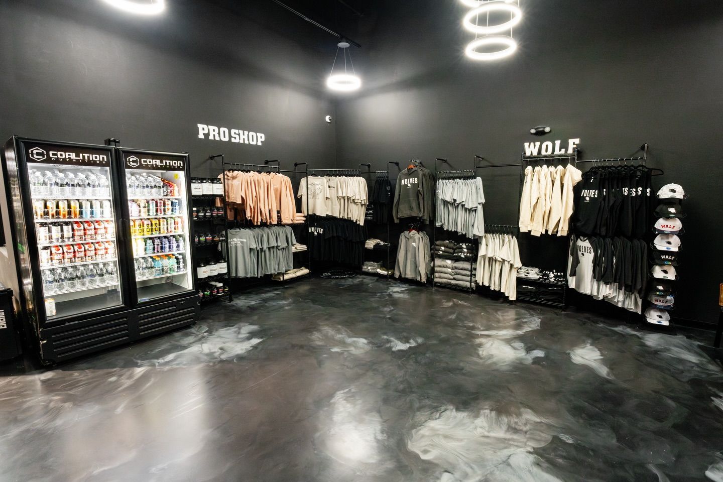 Modern black clothing store interior with racks, shelves, and a wall of merchandise displays