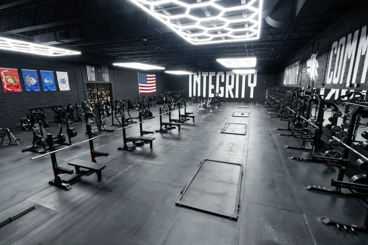 Empty modern gym with black flooring, weight benches, and large wall text reading “INTEGRITY”