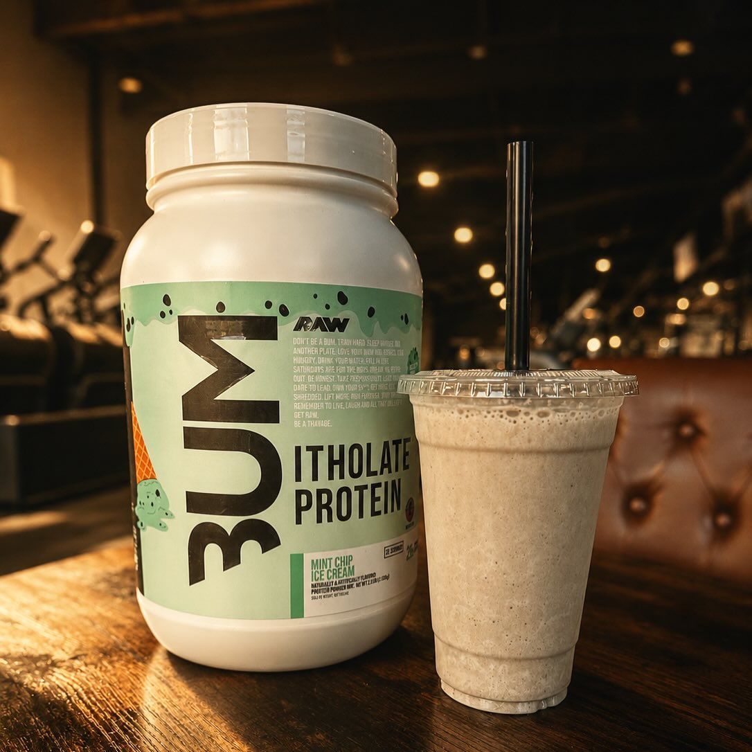 White protein powder jar and creamy smoothie on a wooden table in a dim café-like setting