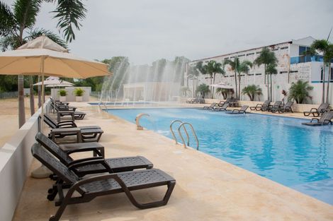 Piscina rodeada de sillas y sombrillas con una fuente al fondo en Ciela Hotel