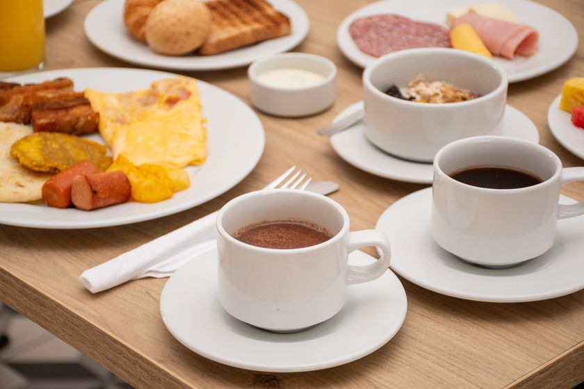 Una mesa cubierta con platos de comida y tazas de café en Ciela Hotel.