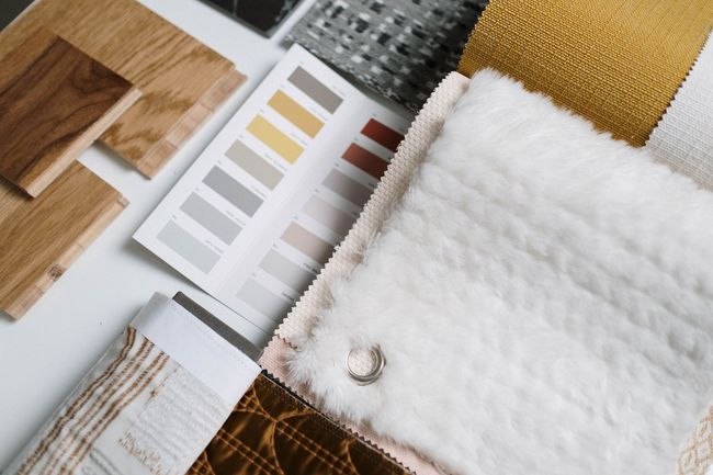 Fabric swatches and color samples arranged on a white surface, with wood and textured material samples.