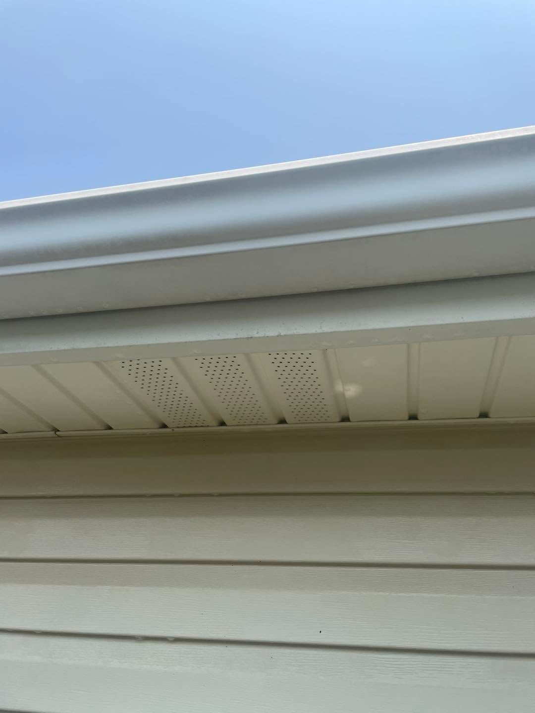 Close-up of white house eaves and soffit under a blue sky
