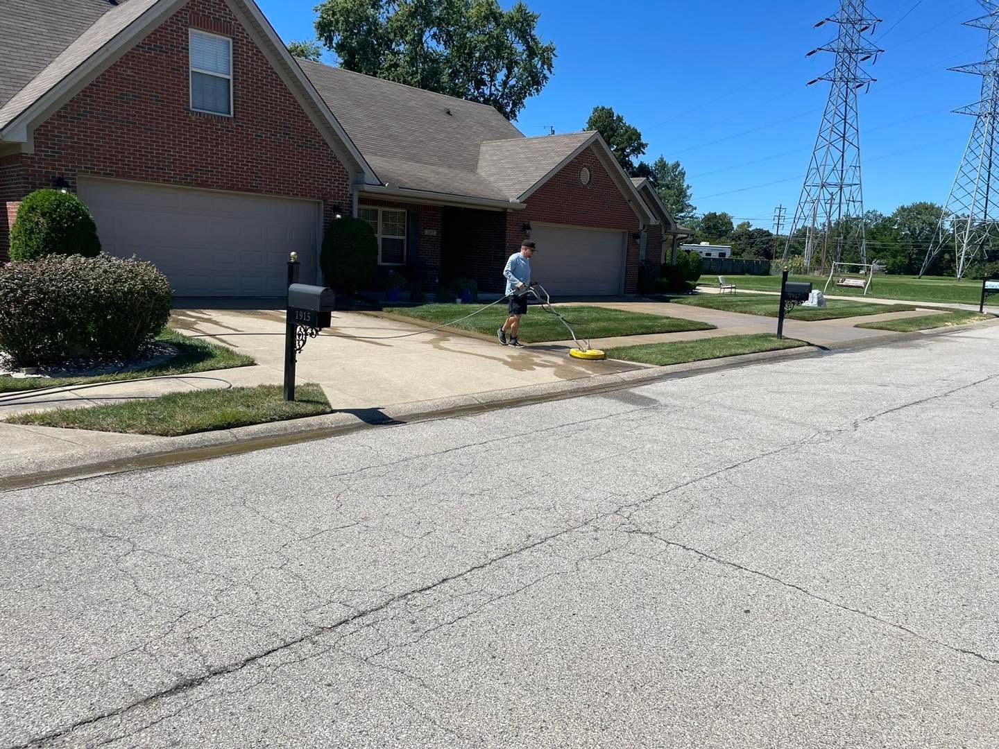 Suburban house with driveway and mailbox; person walking on the lawn near the sidewalk.