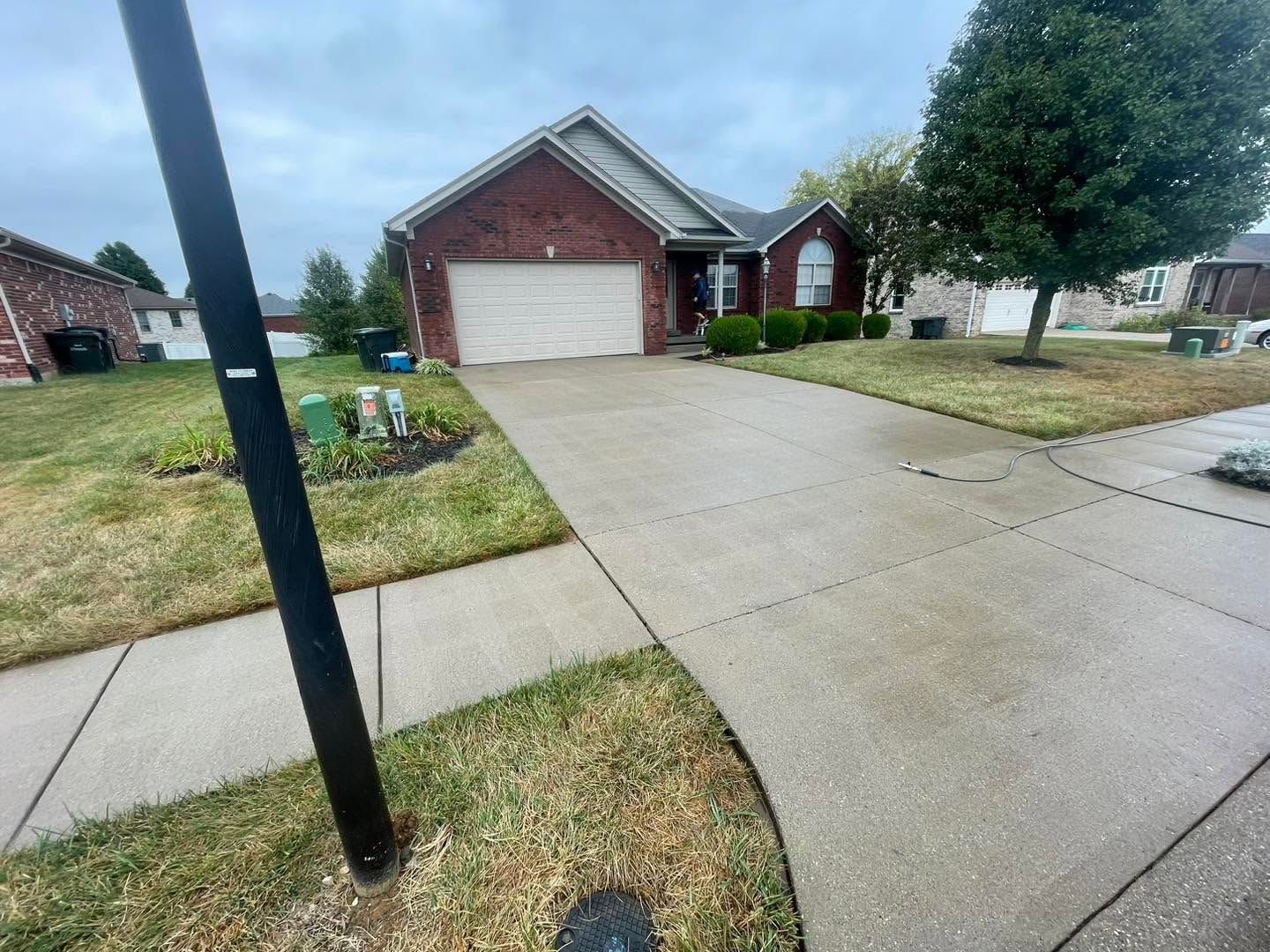 Brick suburban house with a two-car garage and wet driveway on a cloudy day