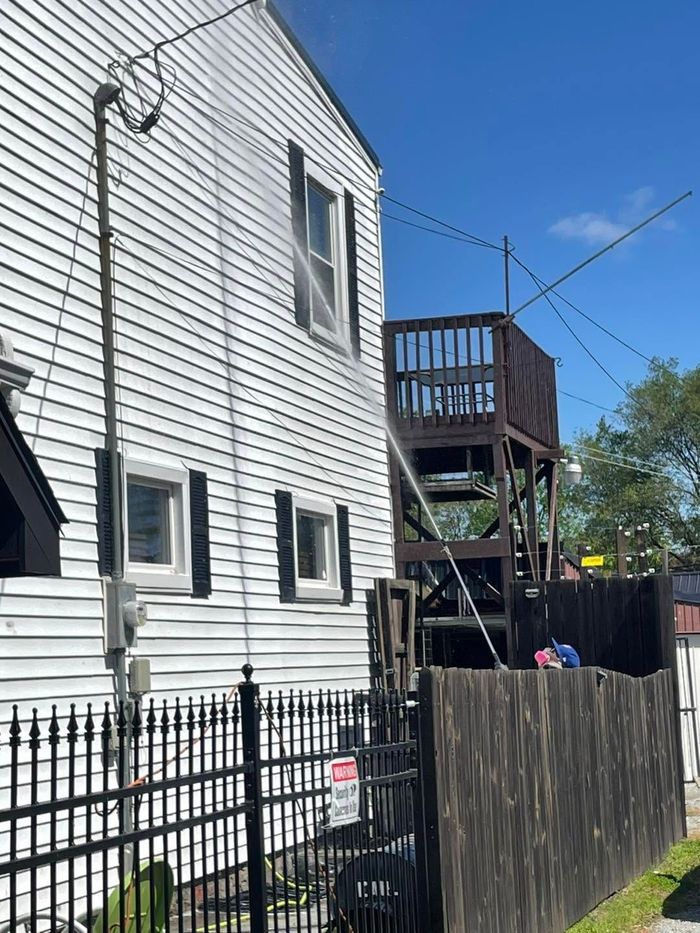 White house exterior with black fence, wooden stairs, and blue sky